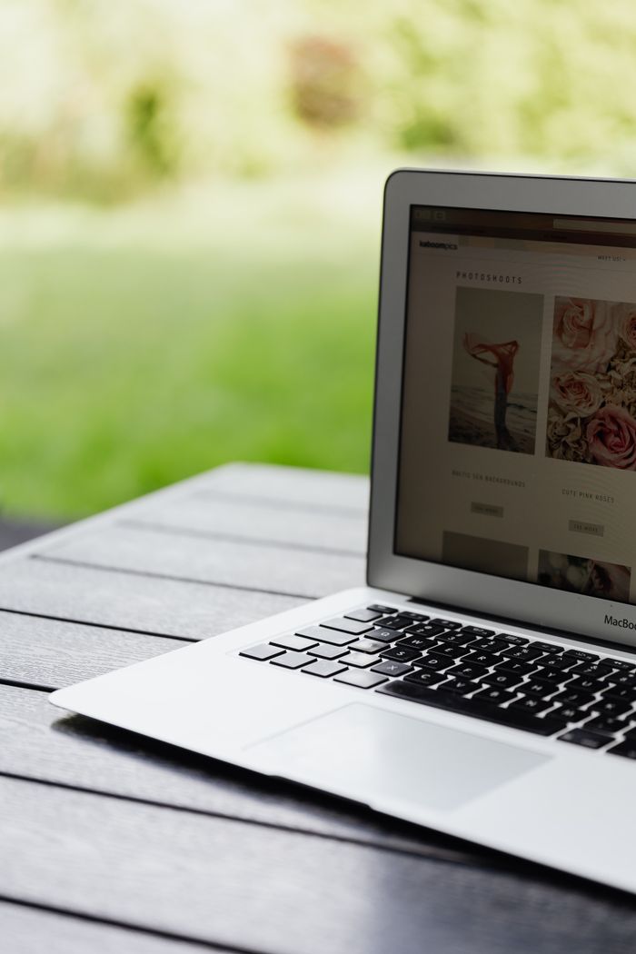 Gros plan sur un ordinateur portable ouvert posé sur une table et affichant un site web en extérieur.